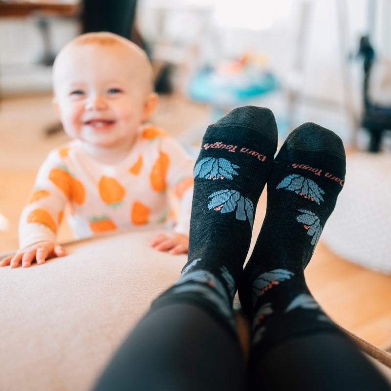 Looking down at feet wearing floral socks, an adorable baby smiling at you