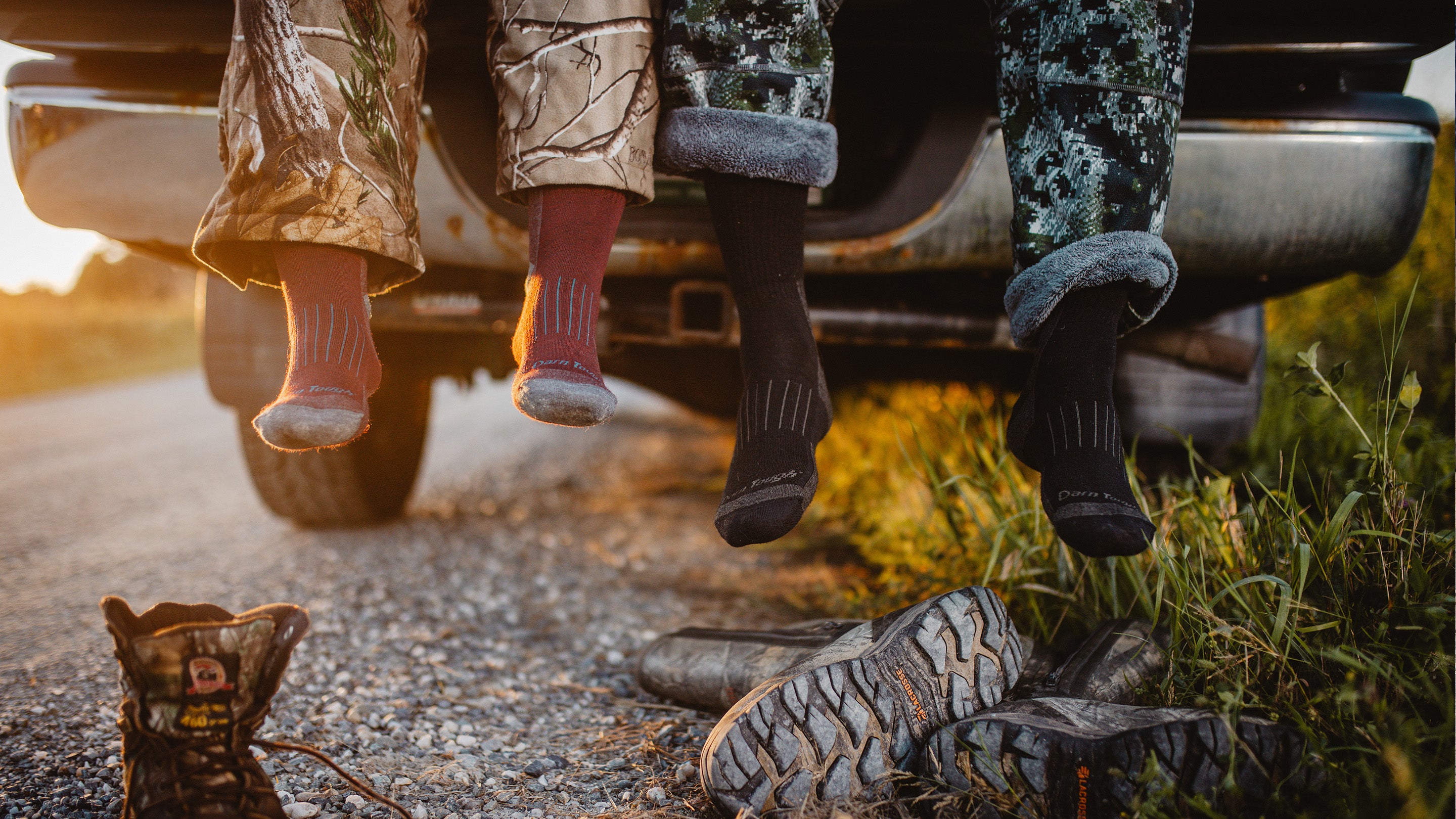 Man and woman in camo wearing darn tough hunting socks about to put hunter boots on