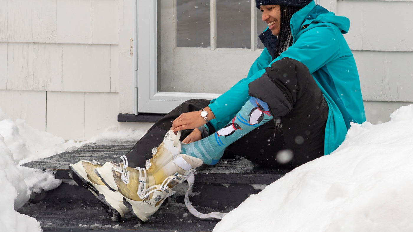 Model putting on snow boots featuring the Women's Penguin peak Ski and Snowboard sock